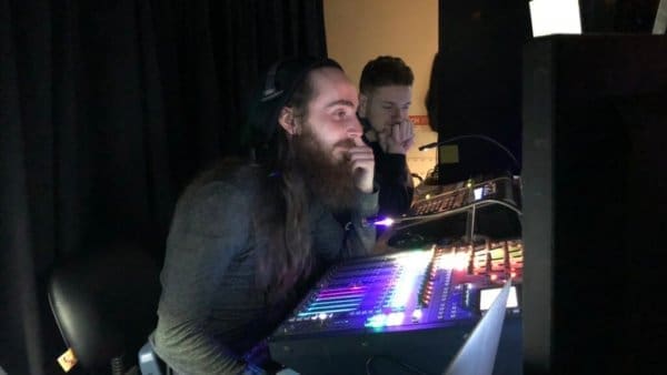 a man with a beard and headphones in front of a dj booth